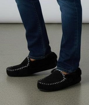 The Skin Thing black sheepskin moccasins with white stitching and EVA sole, worn with blue jeans.