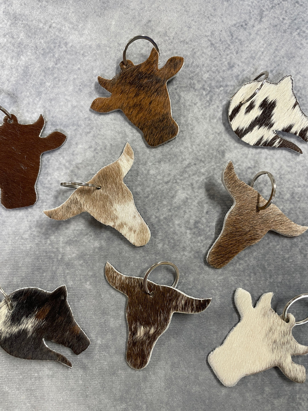The Skin Thing cowhide keyrings in various natural animal print patterns and shapes on a grey background