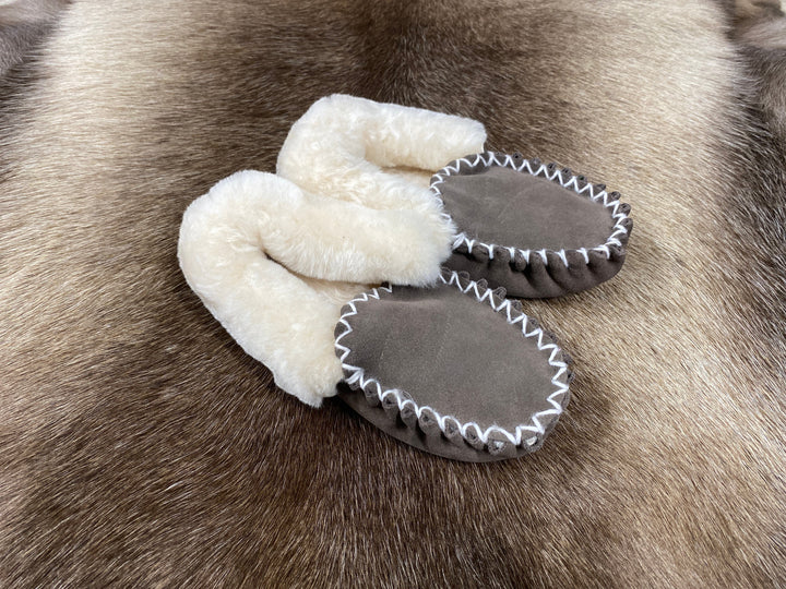 The Skin Thing brown sheepskin moccasin slippers with cream lining and white stitching. Lightweight EVA sole.